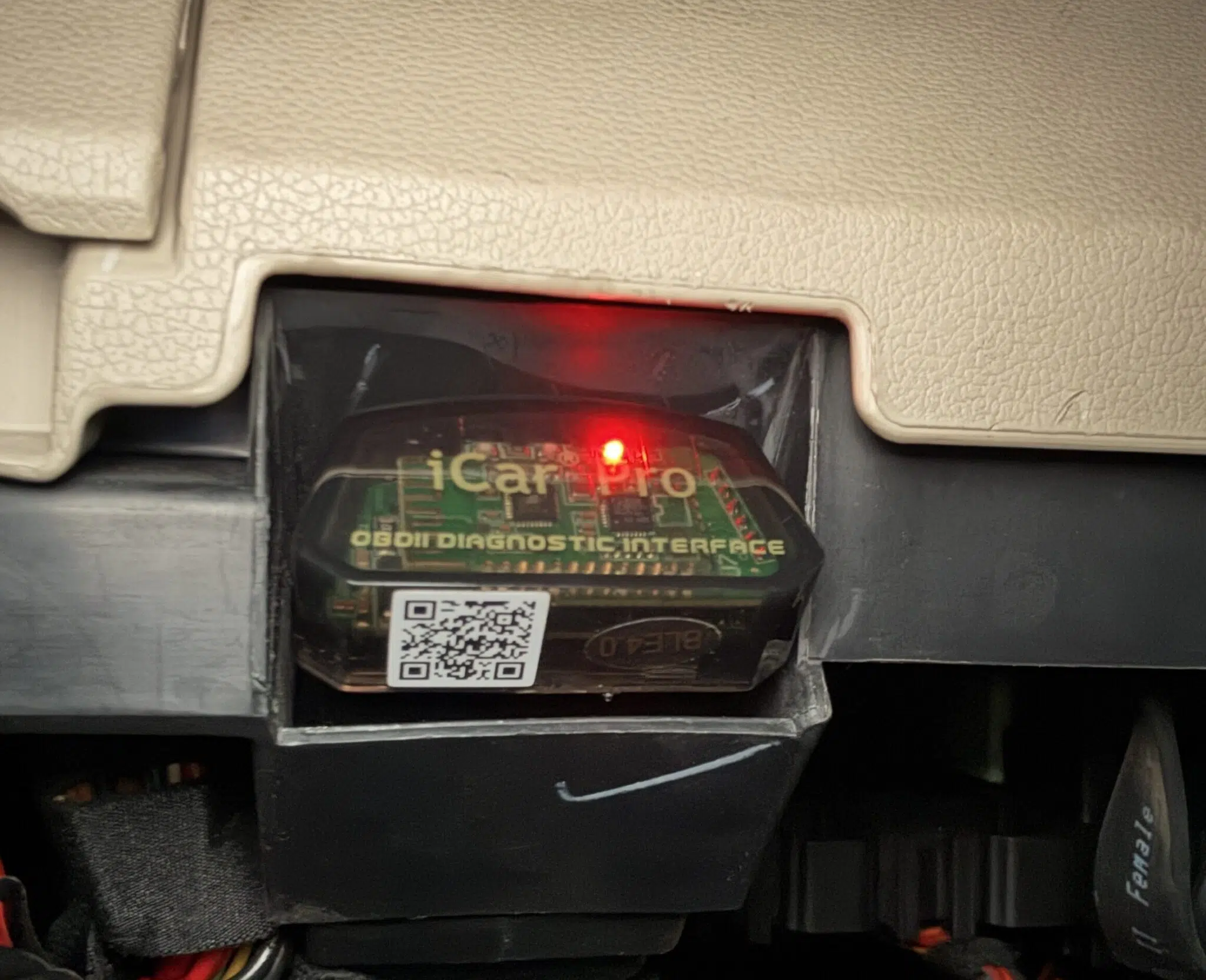 Vgate iCar Pro BLE 4.0 plugged into the OBD2 port under the dashboard of a Skoda Rapid, red status LED lit